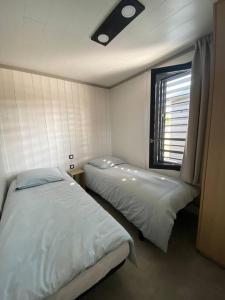 a bedroom with two beds and a window in it at Cottage "SANS SOUCI" chaleureux à 150m de la plage in Jullouville-les-Pins