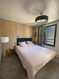 Un dormitorio con una gran cama blanca y una lámpara en Cottage "SANS SOUCI" chaleureux à 150m de la plage, en Jullouville-les-Pins