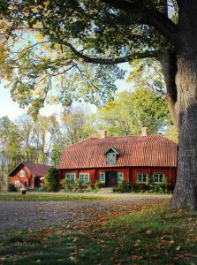 una casa roja con techo rojo y un árbol en Kungs Starby Gård Bed and Breakfast, en Vadstena