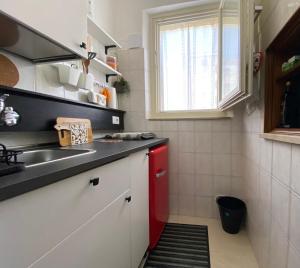 uma pequena cozinha com um lavatório e um frigorífico vermelho em B&B “il Pellicano” em Policoro