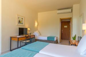 a hotel room with two beds and a desk with a computer at Hotel Hostalillo by Escampa Hotels in Tamariu