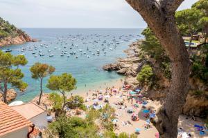 a group of people on a beach with boats in the water at Hotel Hostalillo by Escampa Hotels in Tamariu