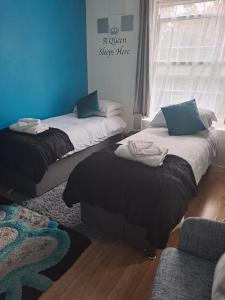a room with two beds and a blue wall at 3 bedroom Brixton Apartment in London