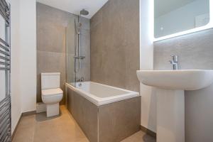 Preston Apartments في بريستون: حمام مع حوض وحوض استحمام ومرحاض