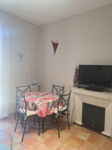 a dining room with a table and chairs and a tv at Le Kallisté in Vaison-la-Romaine