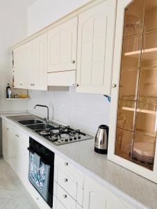 una cucina bianca con piano cottura e lavandino di Daruma Apartment a Siniscola