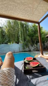 a person laying on a blanket next to a table with watermelon at Villa Adonis with private pool by Lefkadastay in Lefkada Town