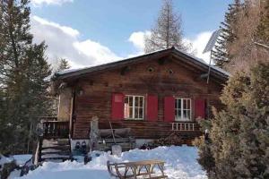 a log cabin with red doors in the snow at Beautiful Swiss chalet with breathtaking views and a sauna in Riein