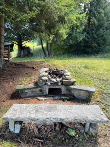 a stone fire pit in a park with a bench at Beautiful Swiss chalet with breathtaking views and a sauna 