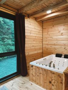 a bath tub in a wooden room with a large window at Kiana Bungalov in Ardeşen