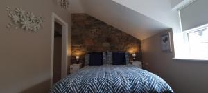 sypialnia z łóżkiem i kamienną ścianą w obiekcie Frontview Cottage - Sleeps 6 w mieście Ballynahinch