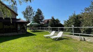 two white chairs sitting in the grass near a fence at Casa Eden in Sâmbăta de Sus