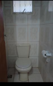 a bathroom with a white toilet and a window at PousadaTopFest in Poços de Caldas