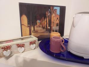 una cafetera y una taza en un mostrador con una pintura en L'Appartamentino, en Bolonia