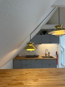 a kitchen with two lights and a sink in a attic at Loftlejlighed i centrum in Ringkøbing