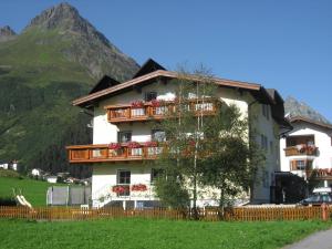 un edificio con balcones y un árbol frente a una montaña en Apart Renate - Silvretta Card Premium Betrieb, en Galtür