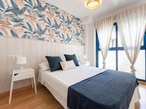 een slaapkamer met een groot bed en een blauwe deken bij Faro's Malaga Citylights - Amazing Roof Terrace in Málaga