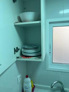 a kitchen sink with a stack of plates in a cabinet at Apartamento “Rubens” in Cullera