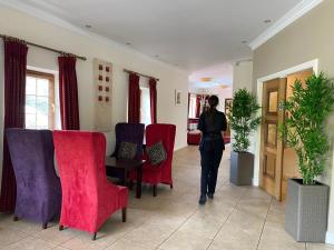 una mujer caminando por un pasillo con sillas rojas y moradas en Hannon's Hotel, en Roscommon