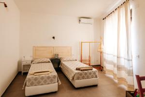 1 dormitorio con 2 camas y ventana en Domo Mediterranea Affittacamere-Guest House, en SantʼAntìoco