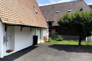 una casa blanca con un garaje y un árbol en triplex dans une ferme rénovée, en Gals 2 fotos más