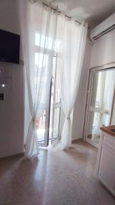 een lege kamer met een raam met witte gordijnen bij L'Incanto del Borgo Antico- Locazione Turistica in Bari