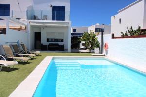 een zwembad met stoelen naast een wit gebouw bij Casa Yaiza in Playa Blanca