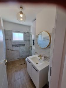 ein Badezimmer mit einem weißen Waschbecken und einem Spiegel in der Unterkunft Apartment with view on city marine in Zadar