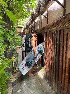 a man is holding a snowboard next to a fence at Coco-Knots Kite - Ilha do Guajiru in Itarema