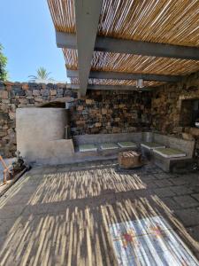 une cuisine extérieure avec un mur en pierre et un plafond en bois dans l'établissement La casa della salemitana, à Pantelleria