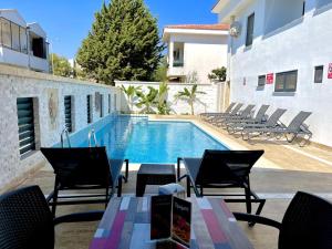 a pool with chairs and a table next to a building at Tahirağa Otel in Datca