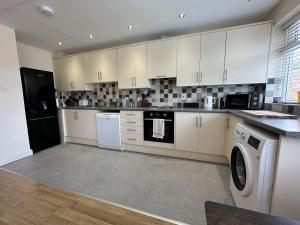 a kitchen with white cabinets and a washer and dryer at Charming 2-Bed Apartment in Danbury essex in Chelmsford