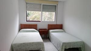 2 camas en una habitación con ventana en albergue bar villamayor, 