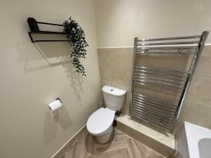 a bathroom with a toilet and a plant on the wall at Charming 2-Bed Apartment in Danbury essex in Chelmsford