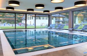 a large swimming pool with chairs in a building at Wellness Hotel Dolomia in Soraga