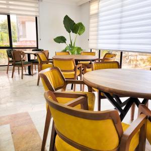 Cashmere Hotel في كوساداسي: مطعم بطاولات وكراسي ونوافذ صفراء