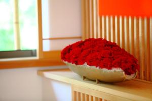 Miska wypełniona czerwonymi różami siedzącymi na stole w obiekcie Sanjoubou Sansou villa w mieście Kioto
