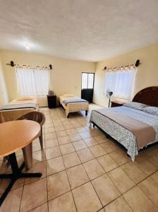 Habitación con 3 camas, mesa y mesa. en Bungalow Cirujano, en Cabo Pulmo