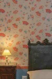 una camera da letto con carta da parati floreale e un letto con lampada di Villa Fenicia a Ruvo di Puglia
