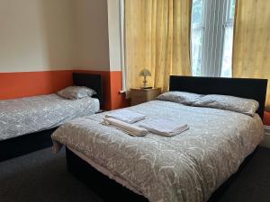 1 Schlafzimmer mit 2 Betten, Handtüchern und einem Fenster in der Unterkunft Malvern Lodge Guest House- Close to Beach, Train Station & Southend Airport in Southend-on-Sea