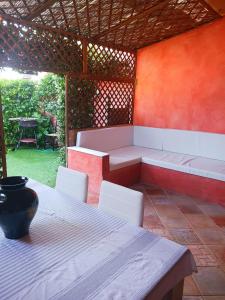 um pátio com uma mesa, cadeiras brancas e um banco em Appartamento Salina Bamba em San Teodoro