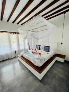 a bedroom with a white bed with a canopy at MITI Beach Bungalows in Nungwi