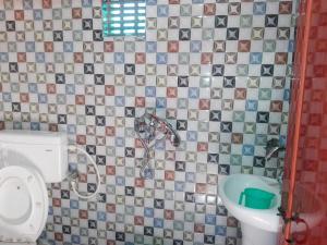 a tiled bathroom with a toilet and a sink at Vamoose Manali Beach Resort in Bhogwe