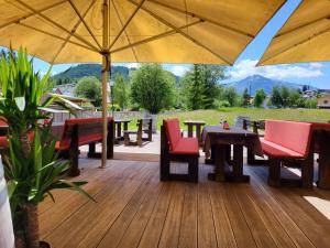 una terraza de madera con mesas, sillas y sombrilla en Wohnung Panoramablick, en Seefeld in Tirol