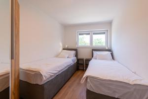 two beds in a small room with a window at Apartman Noa in Kastav
