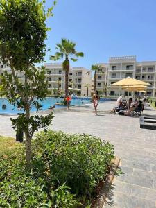 un grupo de personas sentadas alrededor de una piscina en un complejo en Résidence COSTA BEACH 3 IMMEUBLE 10 APPT 1 Bouzinka, en Bouznika