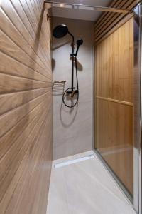 a shower in a bathroom with a wooden wall at Apartman Noa in Kastav
