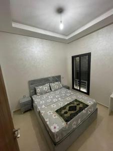 un dormitorio con una cama y una ventana en Résidence COSTA BEACH 3 IMMEUBLE 10 APPT 1 Bouzinka, en Bouznika