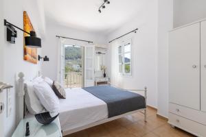 a white bedroom with a bed and a window at Stafylos Green in Skopelos Town