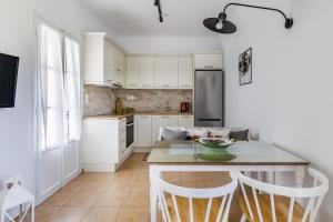 cocina con armarios blancos, mesa y sillas en Stafylos Green, en Skopelos Town